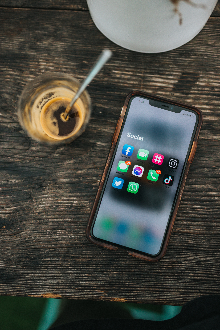 an empty glass of coffee and a cell phone with social media screen open