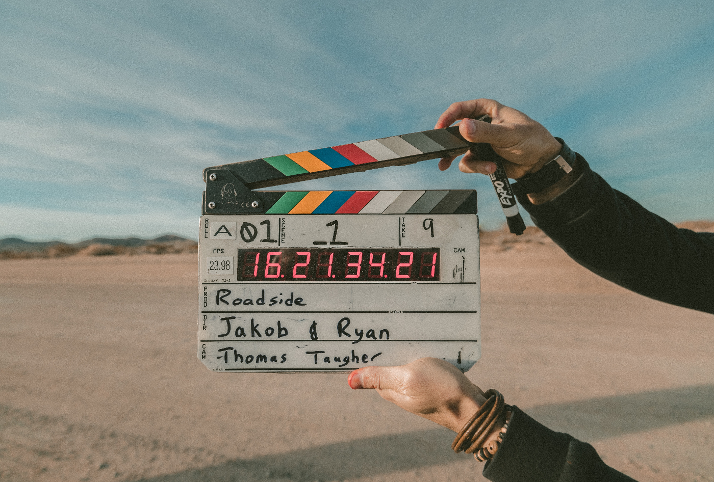 Hands holding up a film clapper in front of a desert