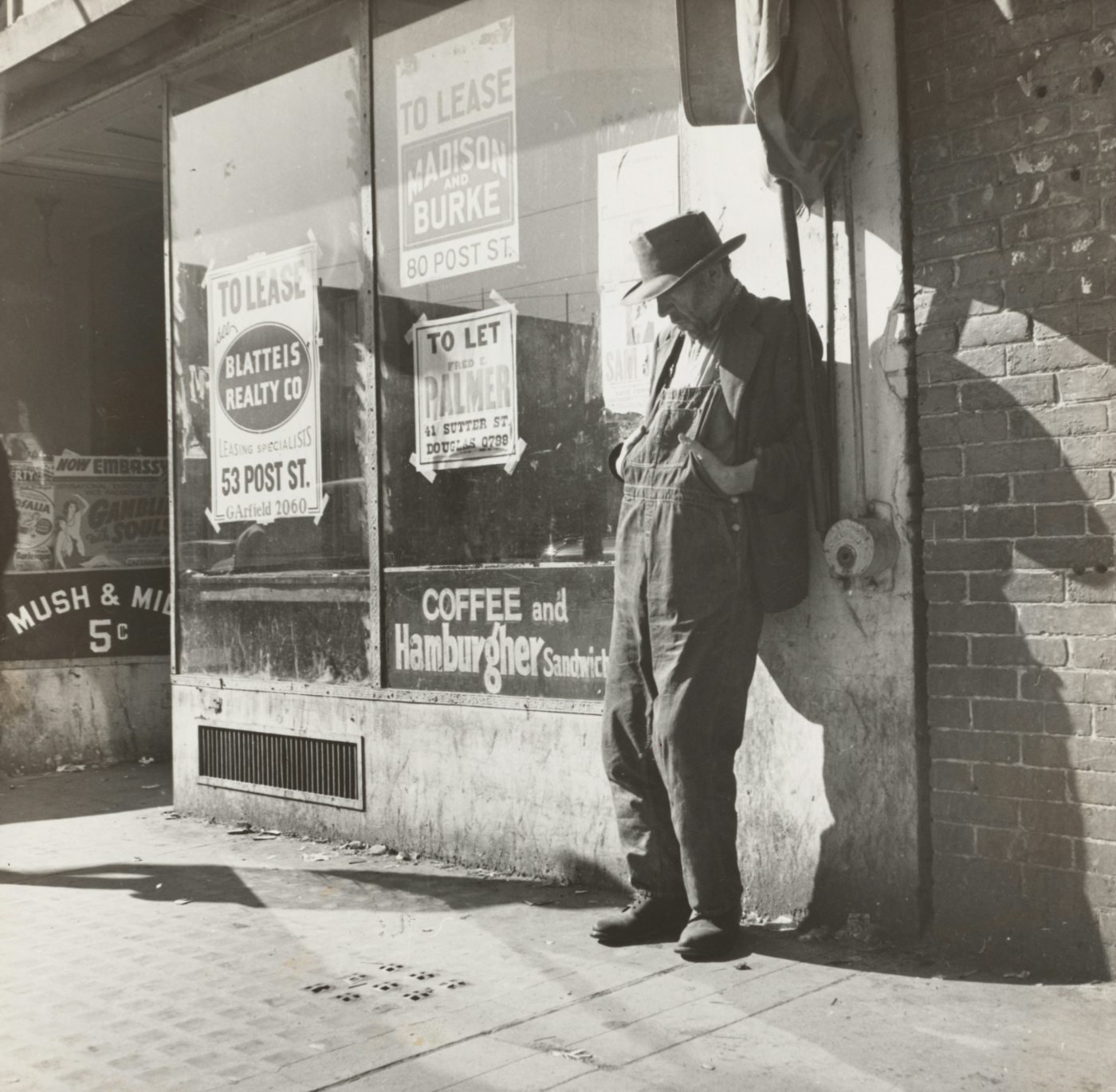 Depression era, man in overalls, stands by a closed diner