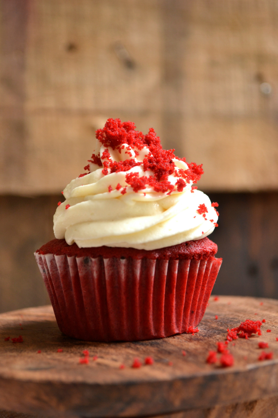 Red velvet cupcake with red crumbles and white frosting
