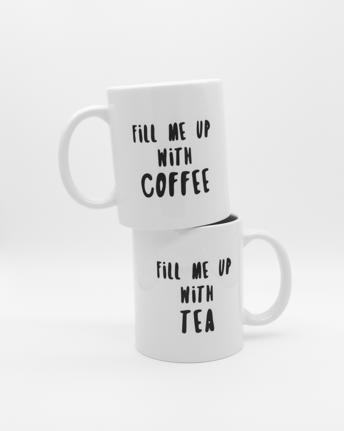 Two white mugs stacked, one reading fill me up with coffee, the bottom one reading fill me up with tea