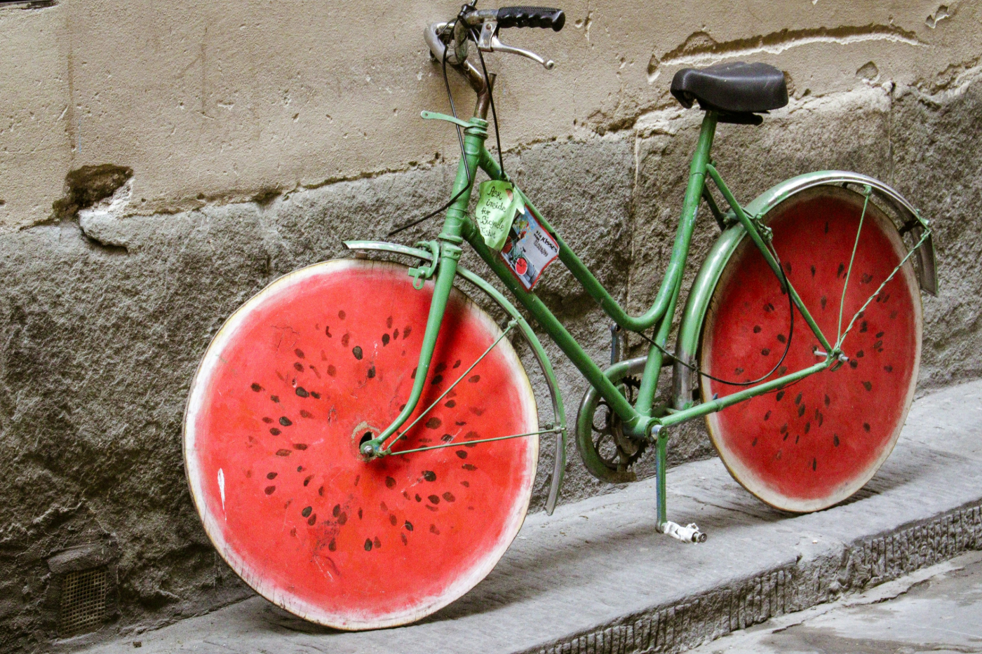 A green bike with wheels that look like round slices of watermelon