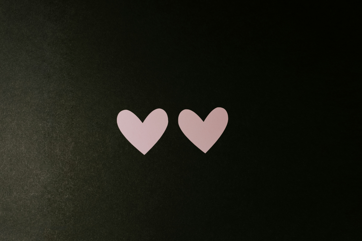 Two pale pink hearts on a black background