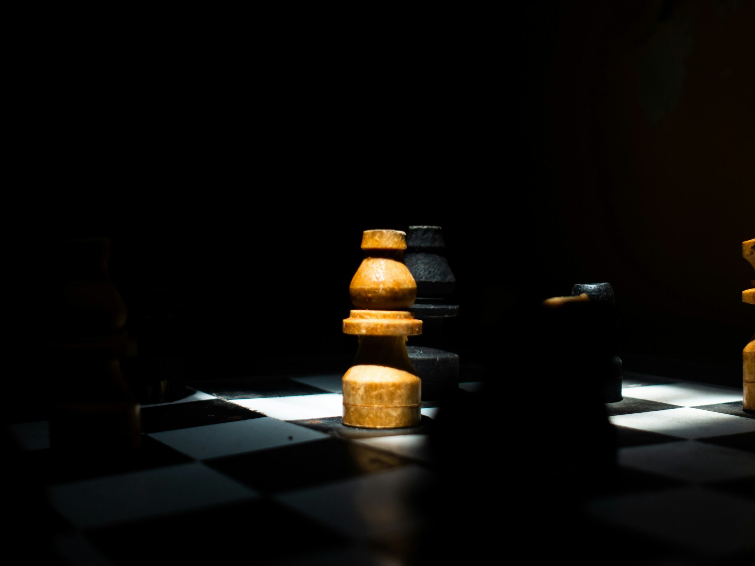 A chess game in dim light with black and yellow pieces