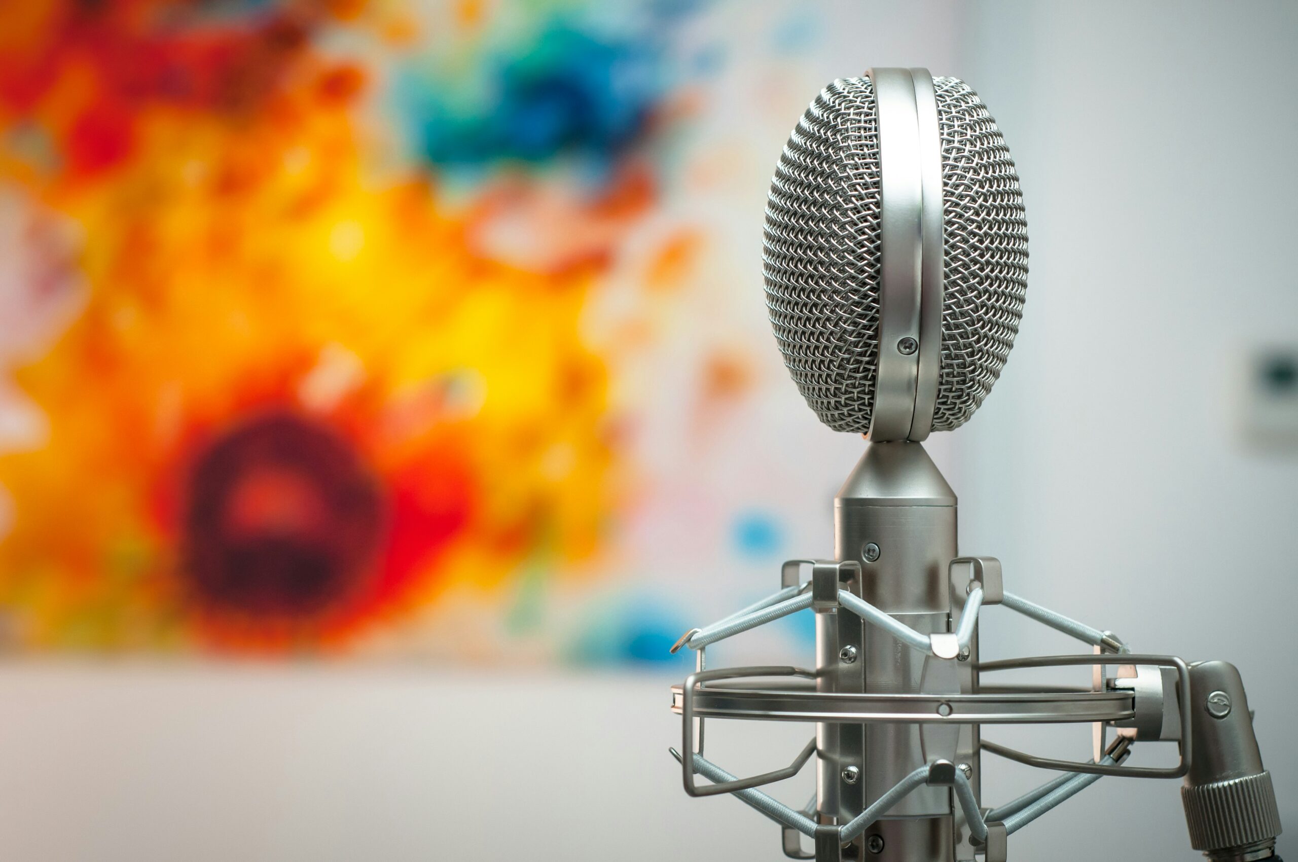 A grey microphone in front of a bright colored painting.