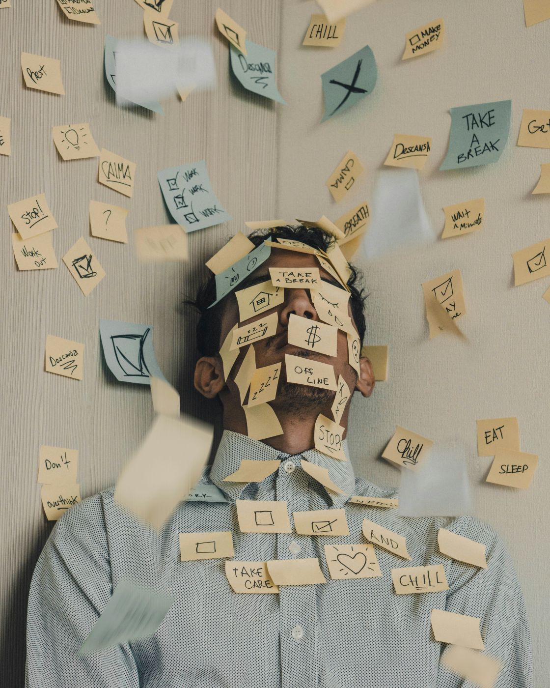 A man standing in a corner, covered with post-it notes