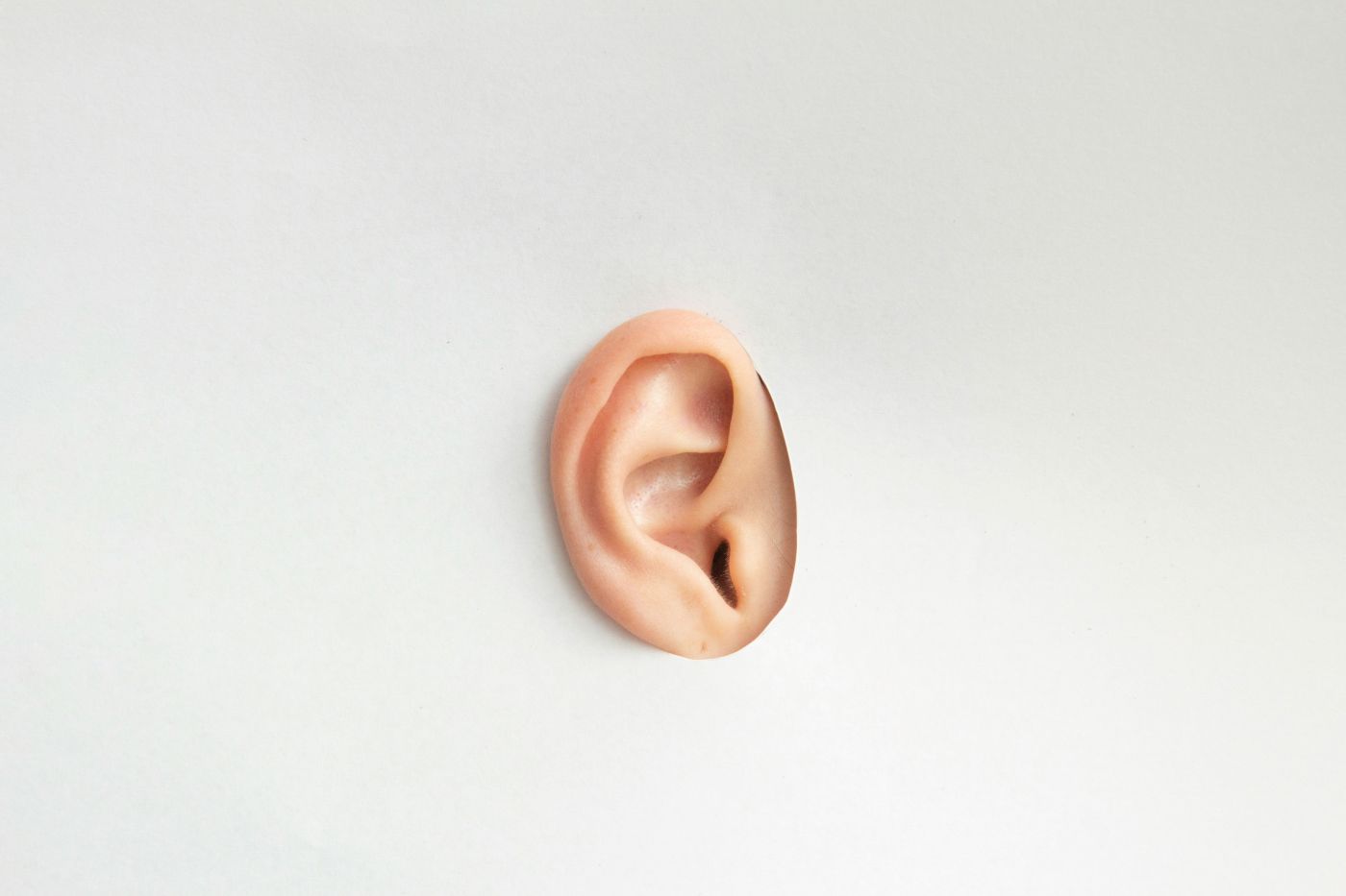 An ear sticking through a sheet of white paper