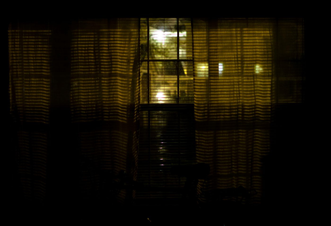 A dimly lit room with blinds on the windows and a bike in the room