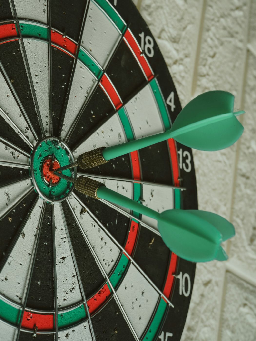 Two green darts in the bull's eye of a dart board