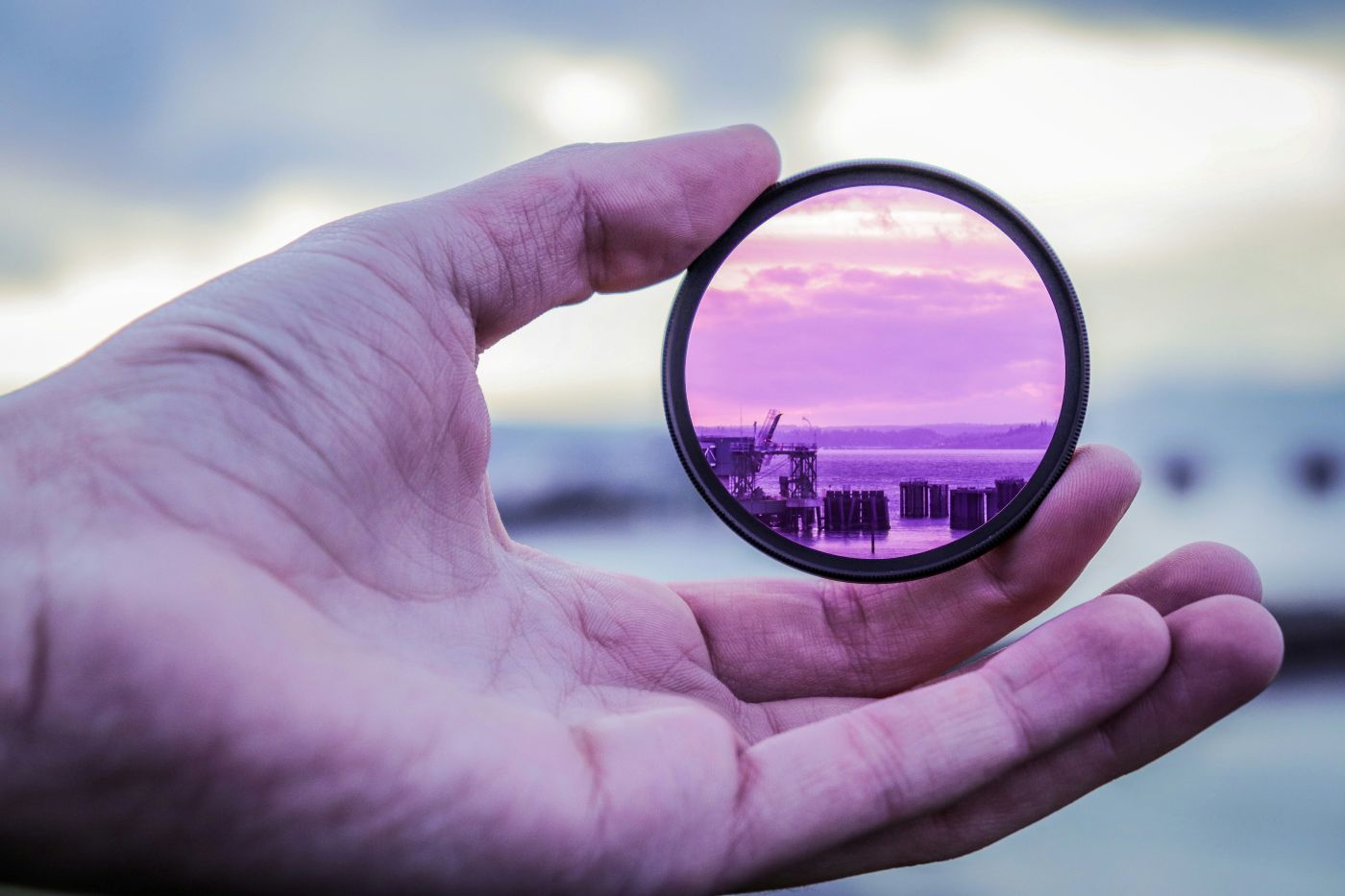 A person holding a camera lens filter