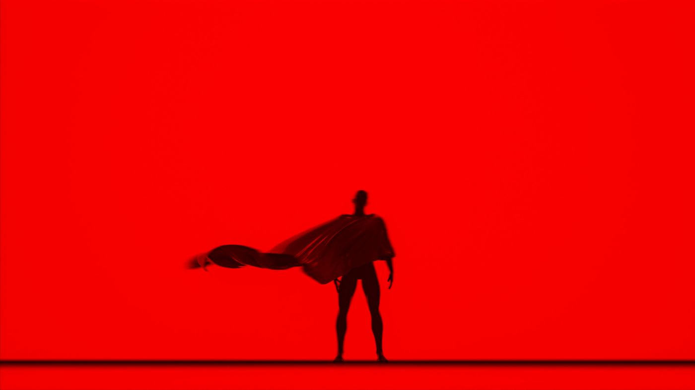 Silhouette of Superman, cape flowing against a red backdrop